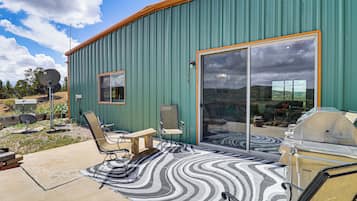 Un bâtiment doté d’un patio avec une porte-fenêtre coulissante, d’un barbecue et de meubles pour s’asseoir à l’extérieur.