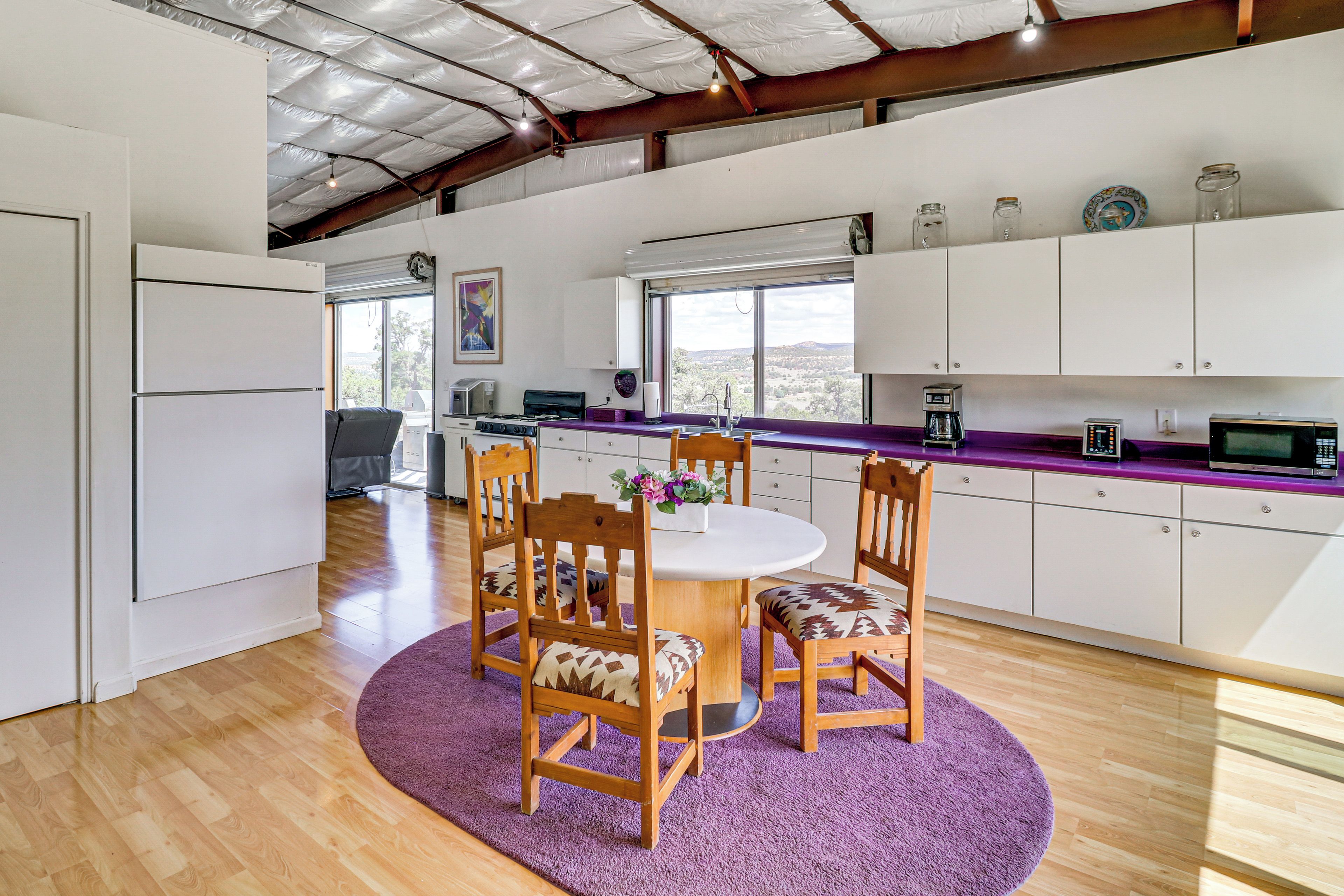 Une cuisine moderne avec un coin repas, comprenant une table ronde, des chaises en bois et un tapis violet.
