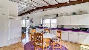 A modern kitchen with a dining area, featuring a round table, wooden chairs, and a purple rug. - Off-grid New Mexico Hideaway Off Hwy 60 (Pie Town)