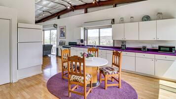 Une cuisine moderne avec un coin repas, comprenant une table ronde, des chaises en bois et un tapis violet.