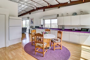 A modern kitchen with a dining area, featuring a round table, wooden chairs, and a purple rug. - Off-grid New Mexico Hideaway Off Hwy 60 (Pie Town)