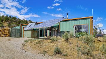A modern house with solar panels, a large window, and a satellite dish.