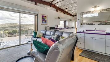 A modern living area with a leather sofa, a dining table, and a kitchen with white cabinets.