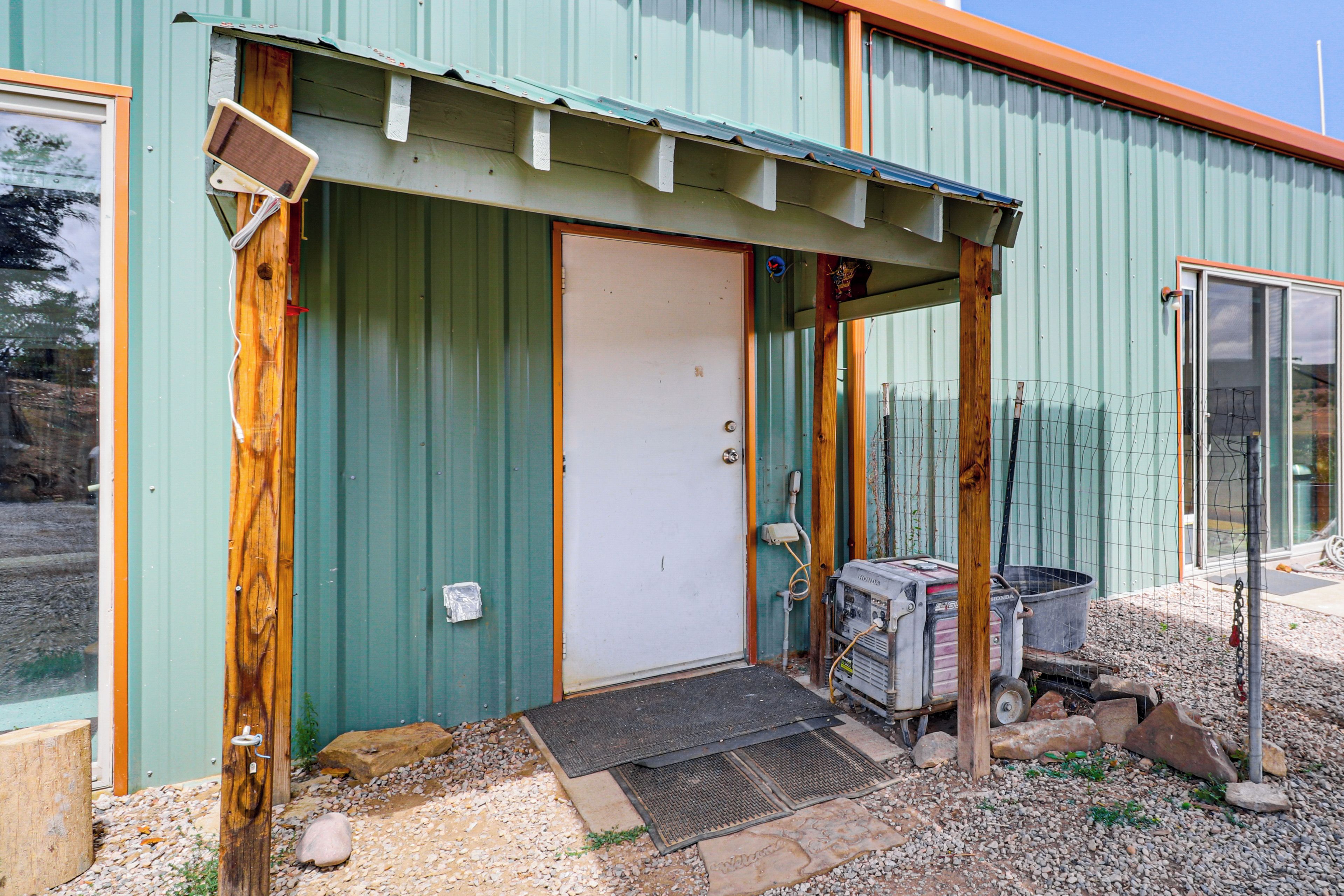 A metal building with a green door, a wooden porch, and a Honda generator outside.