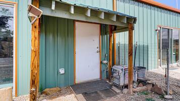 A metal building with a green door, a wooden porch, and a Honda generator outside.