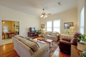 A living room with a sofa, armchairs, a coffee table, and a television.