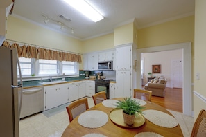 A compact kitchen with white cabinets, a microwave, and a dining area with a table set for four.