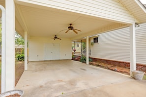 A covered porch with two ceiling fans, a concrete driveway, and a brick border.