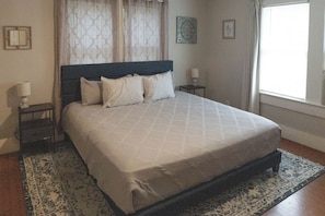 A bedroom with a bed, a nightstand, a lamp, and a window with curtains. - Walk to Main St! Quaint Philadelphia Home w/ Yard (Philadelphia)