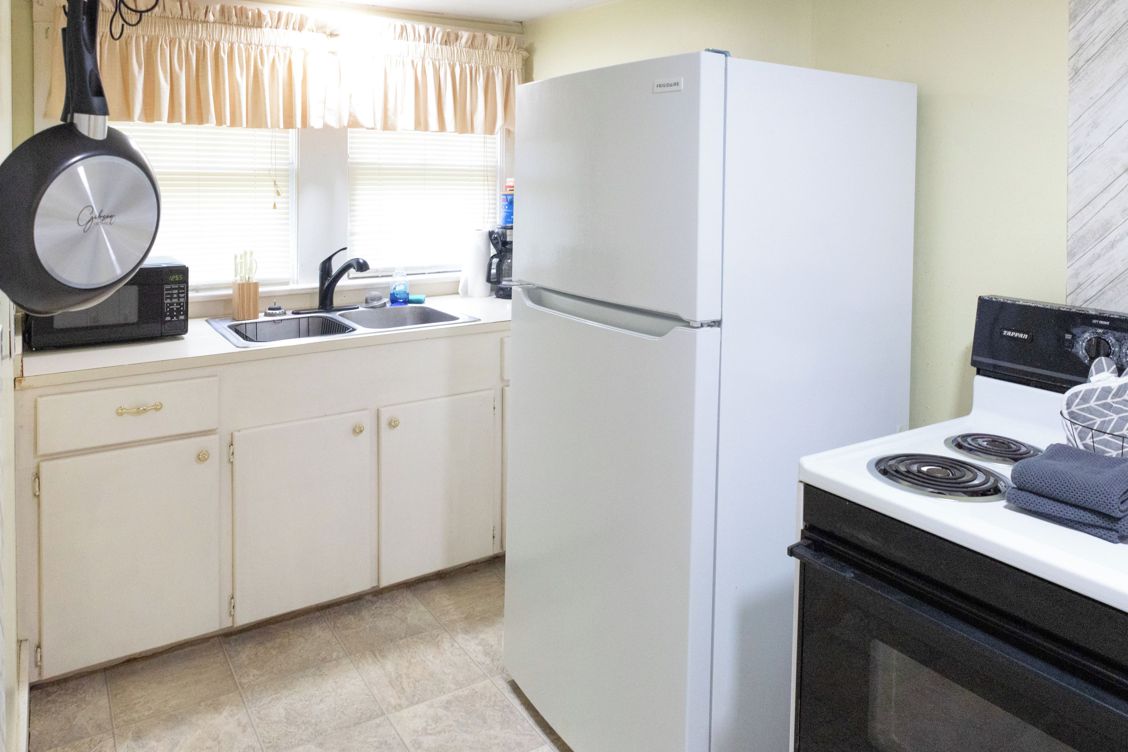 A kitchen with a white refrigerator, a stove, a microwave, and a sink.