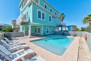 A two-story building with a swimming pool, white deck chairs, and a white picket fence. - No Agenda Hacienda | Private Pool, Game Room, Close to Beach! (Port Aransas)