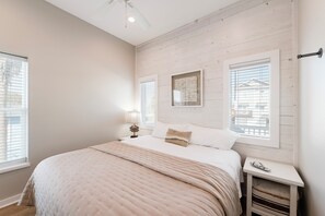 Een slaapkamer met een groot bed, twee nachtkastjes, een venster met zonwering.