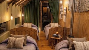 Une pièce confortable avec deux lits, une petite table et un luminaire suspendu.