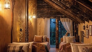 L’intérieur chaleureux d’un chalet avec des murs en bois, un plafond en pente et un lit agrémenté d’un coussin à carreaux.