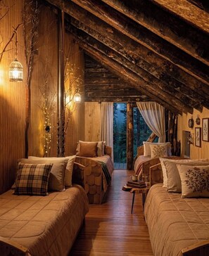 Un interno accogliente di una baita con pareti in legno, un soffitto spiovente e un letto con un cuscino a quadretti.