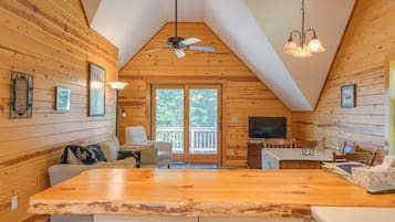 Un intérieur de chalet chaleureux, avec un revêtement en bois, un coin repas et une grande fenêtre.