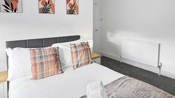 A hotel room with a bed, a bedside table, a lamp, and a radiator.