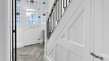 A hallway with a wooden herringbone floor, white doors, and a black metal railing.