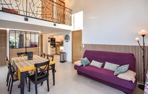 A modern interior with a dining area, purple sofa, and a view of the kitchen.