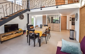 Ein zeitgemäßer Wohnraum mit Treppe, Essbereich, Küche und Fernseher.