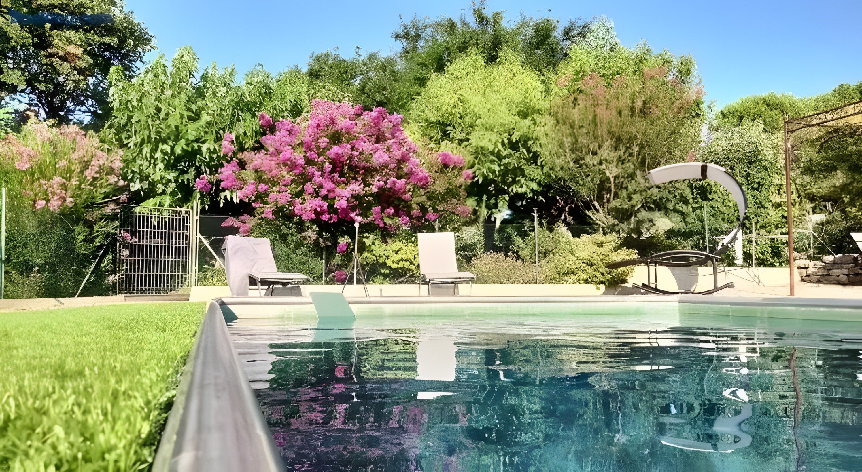 A swimming pool with lounge chairs, a covered seating area, and lush greenery in the background.