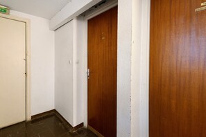 Ein Flur mit einer weißen Tür links, einer Holztür in der Mitte und einer weiteren Holztür rechts.