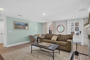 A living room with a sofa, coffee table, and a painting on the wall. - Historic Garden Retreat in the Heart of Downtown Savannah with parking! (Savannah)