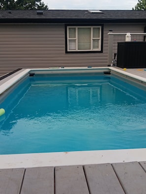 Une piscine rectangulaire entourée d’une terrasse en bois.