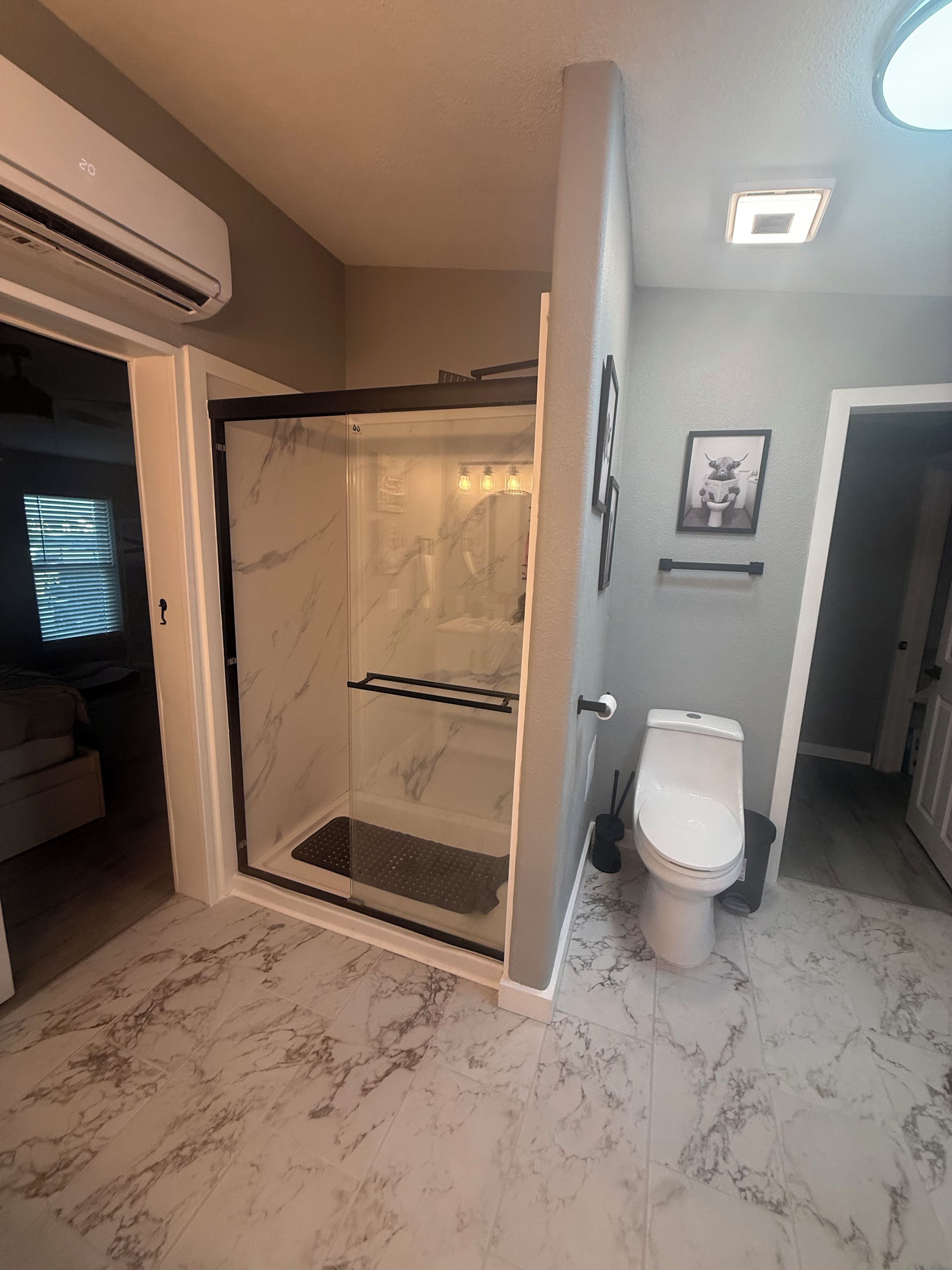 Ein Badezimmer mit einer Duschkabine, einer Toilette und einem Marmorboden.