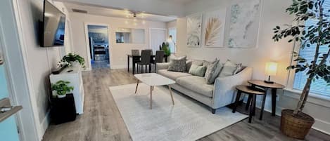A modern living room with a sofa, coffee table, and a TV mounted on the wall.