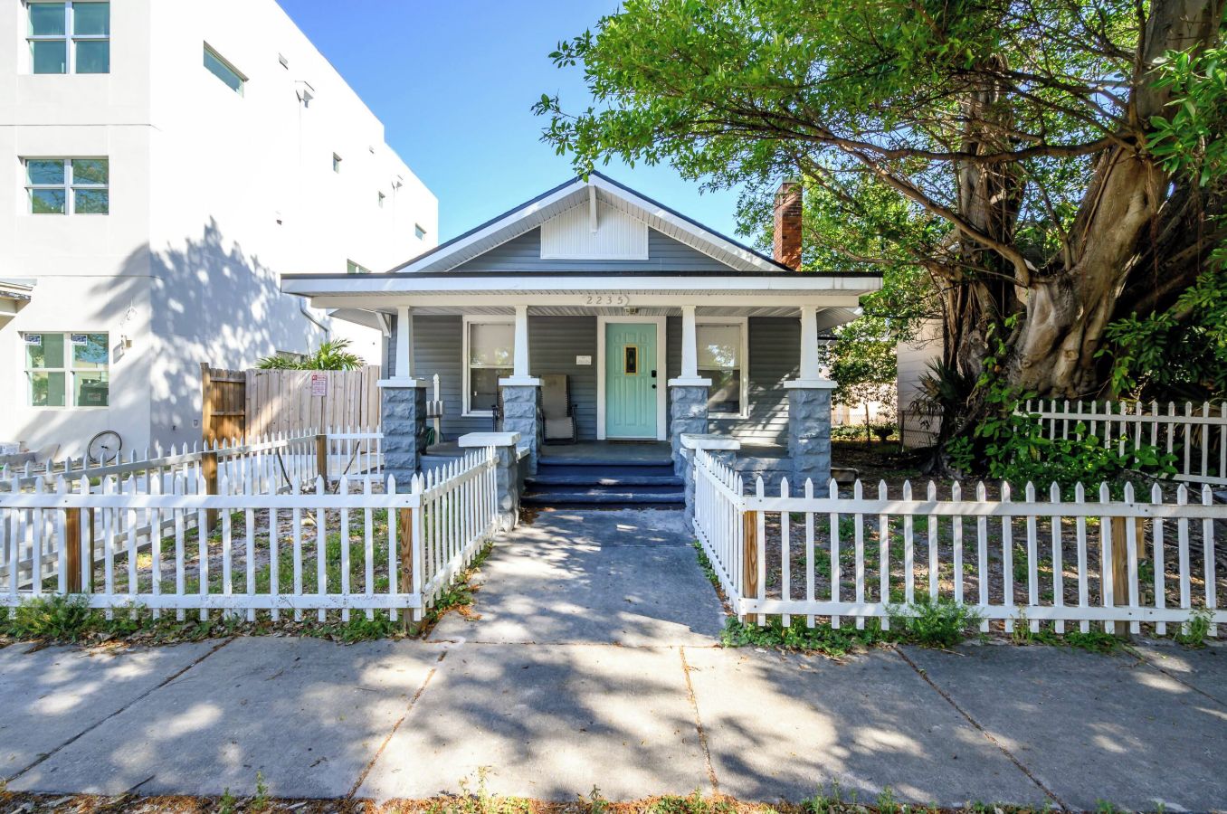 A two-story house with a front porch, a mailbox, and a white picket fence.