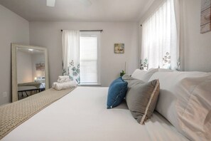 A bedroom with a bed, a mirror, a window with curtains, and a bedside table. - Entire rental 2 bed unit in St. Petersburg, Florida - PRIME LOCATION! (St. Petersburg)