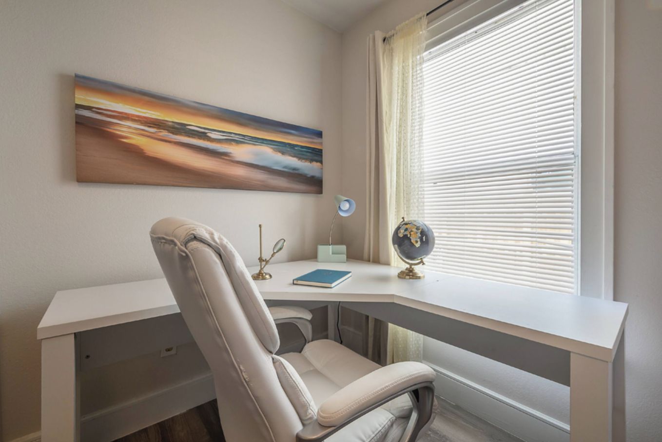 A study room with a desk, a chair, a globe, and a painting on the wall.