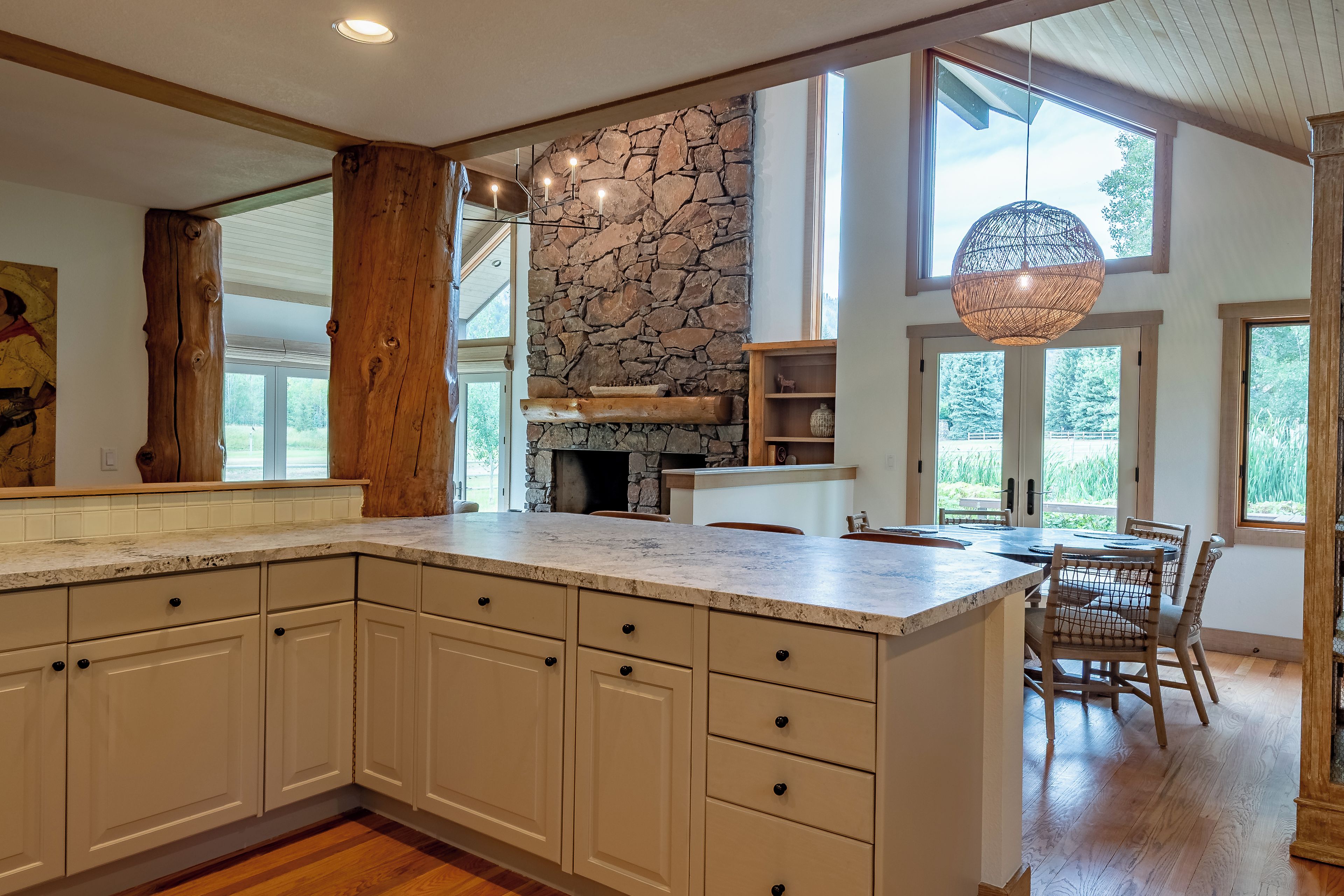 A spacious kitchen with a large island, stone wall, and a dining area with a view.