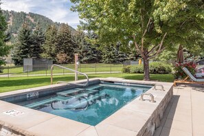 A rectangular swimming pool with a metal ladder, surrounded by a fence, with trees and a grassy area in the background. - Weyyakin Home 307- Amazing Home Minutes From Downtown & Skiing (Sun Valley)