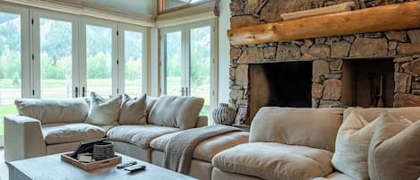 A modern living room with a stone fireplace, large windows, and a sectional sofa.