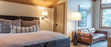 Un dormitorio con cama, sofá, lámpara y un cuadro en la pared.