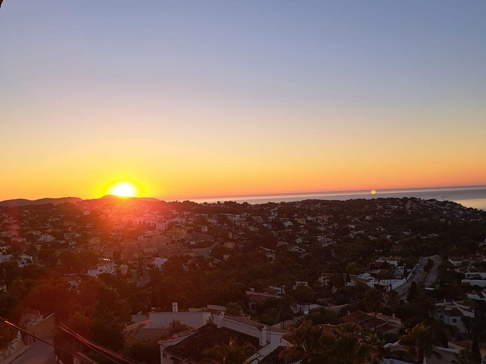 Une ville côtière au coucher du soleil, avec des bâtiments et un ciel dégagé.