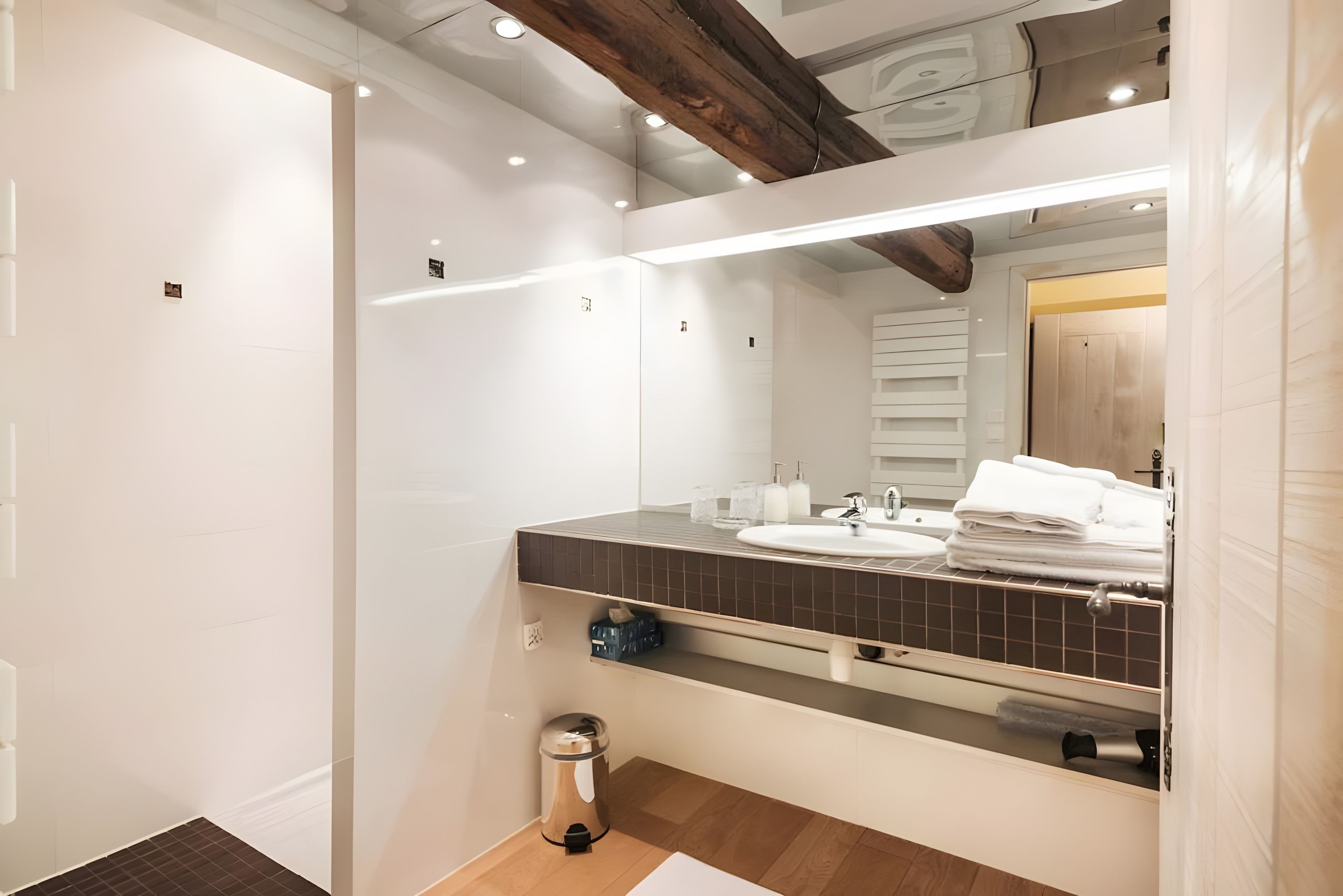A modern bathroom with a large mirror, a sink, and a toilet.
