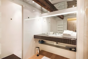 Casa de banho moderna com um espelho grande, lavatório e sanita.