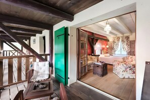 A wooden staircase leading to a room with a bed, a green door, and a view of the outdoors.