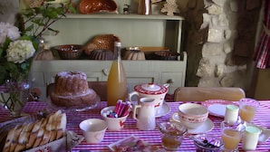 A dining table set with a variety of food items, including bread, figs, and cheese, and a bottle of juice. - La Ferme de Sophie - Josepha Room (Kleingœft)