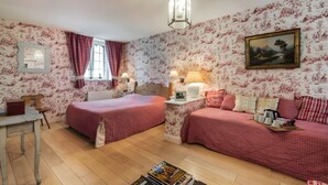 Une chambre avec deux lits, une table de chevet, une table et un tableau au mur.