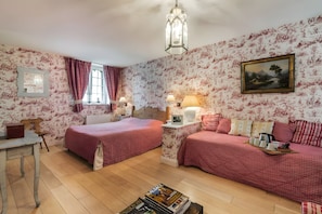Quarto com duas camas, mesa de cabeceira, uma mesa e um quadro na parede.