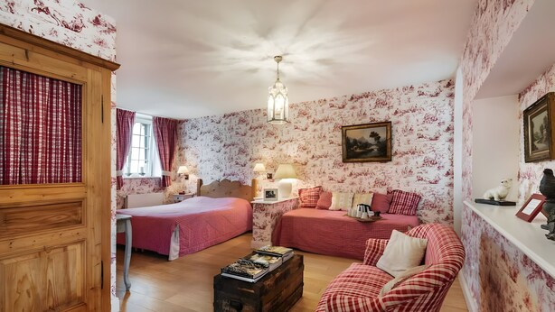 Une pièce comprenant un lit, un canapé, une commode, un bureau et une lampe.