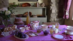 Une table à manger dressée avec différents plats, une bouteille et un tableau accroché au mur.
