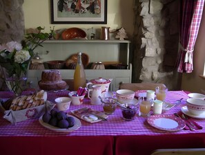 Mesa de jantar posta com diversos pratos, uma garrafa e um quadro na parede.