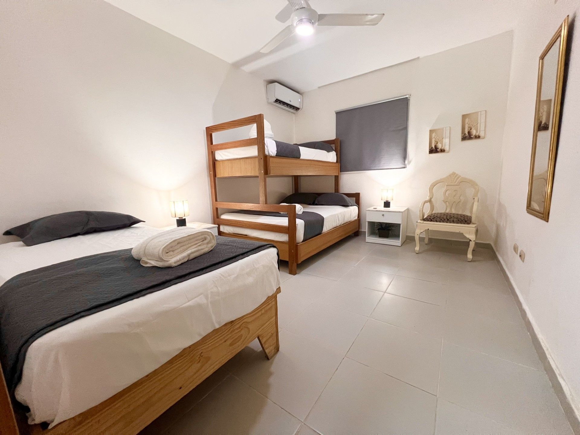 Un dormitorio con dos camas literas, una silla, una mesita de noche y un ventilador de techo.