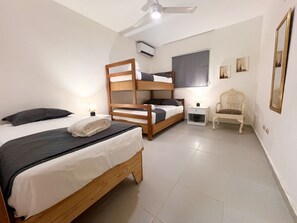 A bedroom with two bunk beds, a chair, a bedside table, and a ceiling fan. - Villa La Escapada - Private Caribbean Oasis Near Juan Dolio Beach (San Pedro de Macorís)