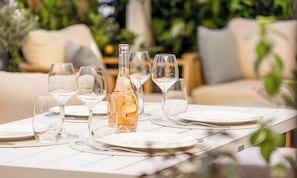 A table set for dining with clear glassware and a bottle, surrounded by greenery. - ELEGANT 2-BEDROOM CANNES HOME 50M FROM THE CROISETTE WITH 25M² TERRACE (Cannes)